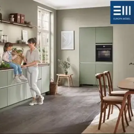 Grüne Küche mit zwei Personen, Kind, Esstisch und Logo Europa Möbel